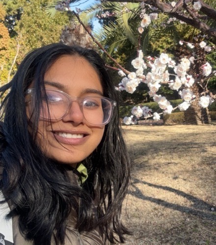 Sruthi, founder of learningwithsruthi, outdoors under a blossoming plum tree